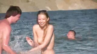 A mature woman sunbathes naked on the sandy beach