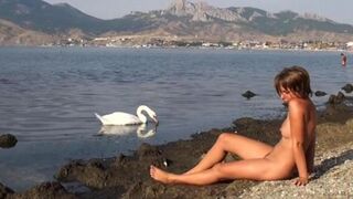 A completely naked girl is having fun on the riverbank. It's very refreshing!