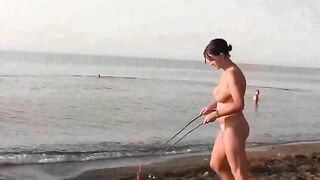 A naked girl is having fun on the beach, showcasing her body