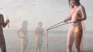 A naked girl is having fun on the beach, showcasing her body