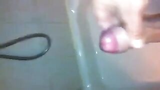 The kid masturbates his dick in the shower stream