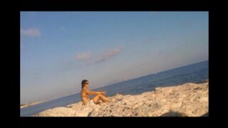 The girl sunbathes naked on the beach